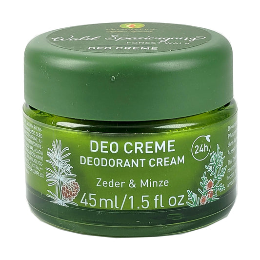 Primavera Deocreme Waldspaziergang im grünen Glastiegel. Aufschrift der Produktbezeichnung und der beiden duftgebenden Inhaltsstoffe Zeder und Minze; daneben die Angabe der Wirkdauer bis 24 Std. ; darunter die Inhaltsangabe 45ml; links und Rechts flankiert von je einem skiziertem Pinienzweig mit einigen Zapfen.